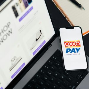 A mobile phone with OXXO Pay on a laptop used for online shopping.
